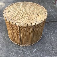 Round wicker ottoman showing woven natural wicker strands with reinforced edges.