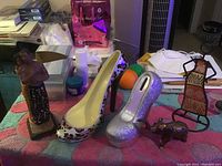 Figurines and shoe banks placed on a colorful towel background with miscellaneous items in the background
