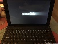 Smartab laptop powered on showing Smartab logo on screen, keyboard visible.