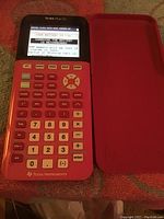 TI-84 Plus CE calculator with matching red protective cover, screen shows low battery warning