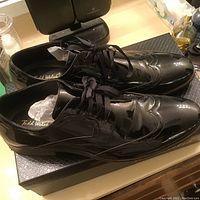 Pair of black shiny patent leather men's dress shoes on Todd Welsh box.