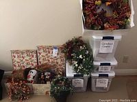 Overview of assorted autumn and spring decor items, wreaths, decorative boxes labeled Christmas and Victorian seasonal themes, and small figurines.