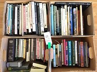 Four boxes filled with various books on different themes including decorating, flowers, religion, and a special edition children's book.