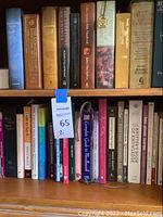 Wide view of two wooden shelves filled with assorted books varying in size, color, and subject matter including theology, knitting, language, and self-help.