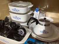 Photo showing full collection of Corningware items including coffee pot, baking dishes both large and smaller, and black detachable handles.