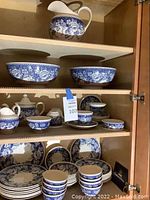 Cabinet shelf showing pitcher, serving bowls, sugar bowl, creamer, teacup and saucer