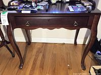 Front view of wooden desk showing single drawer and polished dark wood finish.