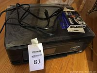 Top view of Epson XP-410 printer with power cable and unopened ink cartridge box on top.