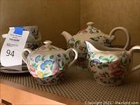 Tea service with teapot, sugar bowl, and creamer showing floral pattern and shape