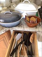 Overview of white ceramic baker, grey enameled cast iron casserole, cranberry mold and utensil drawer