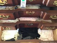 Drawer with folded white lace garment, black fabric, floral prints, and pink nightwear