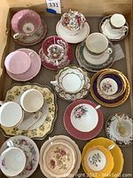 Overview of tea cups and saucers showing assorted colors, shapes, and patterns in a box