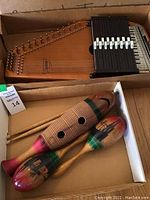 Oscar Schmidt autoharp with metal strings and black chord bars in cardboard box, along with two painted maracas and a wooden percussion instrument with ridges and sticks