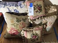 Image showing five assorted needlepoint pillows with floral designs, various sizes and crochet edges on some.