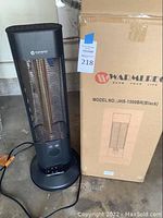 Full view of Warmlite space heater standing next to its original box with product label and model number visible.