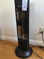 Full view of the Warmrec black space heater tower standing on wooden floor, unplugged.