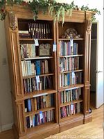 Front view of two large wooden bookshelves filled with books and decorative items. Shelves are carved with ornate detailing.