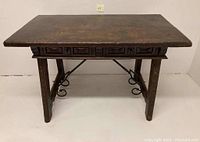 Full front view of carved walnut writing table showing apron, legs and wrought iron stretcher