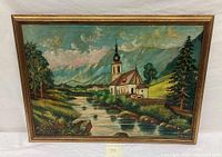 Full view of the oil painting depicting a European old church beside a river, rural landscape with mountains in background.