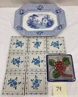 Photo of blue and white scenic transferware platter and nine Italian ceramic tiles, eight with blue floral patterns and one with grape design.