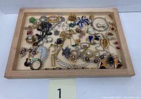 Full view of costume jewelry pieces arranged on a wooden tray showing various necklaces, earrings, brooches, and bracelets.
