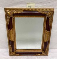 Full image showing the mirror front with gold gilt ornate corners and beveled glass.