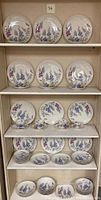 Full set of vintage Castleton China Wisteria pattern including plates, bowls, cups, and saucers arranged on shelves.