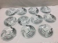 Full view of all 12 plates arranged in rows, showing the fused glass floral bird design.