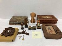 Photo showing the full lot including the two wooden vanity boxes, carved wooden elephant, painted woman figure, miniature jeep, carved figurines, disassembled clock parts, and framed sand art portrait.