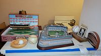 Overview of the lot including Ebbets Field model stadium, game, plaque, baseball, card, and ashtray on table