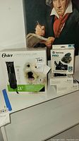 Lot contents showing Oster A5 clipper in original box alongside three Yaktrax Pro traction device boxes.