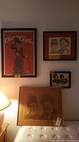Four pieces of comedian themed wall art on wall, lamp on side for scale.