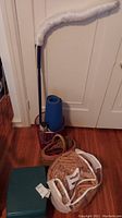 Photo showing duster, blue rolled mat, woven straw bag in clear bag, and green plastic step stool on hardwood floor
