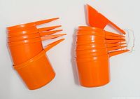 Two stacked sets of nested vintage orange Tupperware measuring cups with pointed handles and pouring spouts
