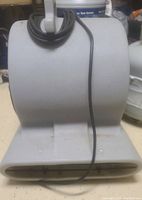 Front view of gray plastic floor air mover fan with cord wrapped around the handle