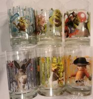 Photo of six collectible glasses featuring Shrek, Donkey, and Puss in Boots with colorful backgrounds.