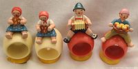 Set of four Erzgebirge Wendt & Kuhn Expertic wooden napkin rings with Girl and Boy figures sitting on top of yellow and red cylindrical bases.