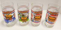 Photo showing four McDonald's McVote 86 glasses with various burger cartoon graphics including a hamburger and cheeseburger design.