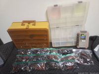 Photo showing two fishing tackle boxes, one yellow-brown and one clear plastic, along with multiple plastic bags containing assorted vintage rubber worms and a small digital scale.