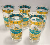 Five clear glass tumblers with turquoise and gold painted designs of the Virgin Islands, no chips or cracks visible.