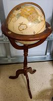 Full view of globe mounted on wooden stand with tripod legs