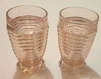 Pair of pink ribbed glass tumblers with rounded bubble bases shown side by side