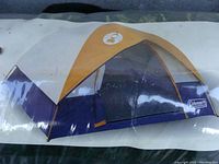 Photo of Coleman Sunrise III tent shown fully assembled with dome shape and yellow/white/blue colors.