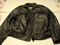 Front view of black Harley Davidson leather jacket showing full zipped front, zippered pockets, and ribbed hem and cuffs.