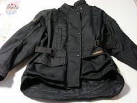Full front view of the black Joe Rocket motorcycle jacket laid flat showing design, pockets, adjustable straps, and collar.