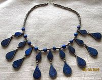 Front view of tribal necklace showing blue lapis lazuli teardrop pendants and metal beads stringing with hook clasp.