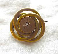 Front view of a round Victorian love knot brooch with matte finish and diamond center stone.