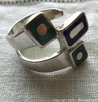 Close-up of the vintage sterling silver ring showing the enamel geometric shapes in green and blue.