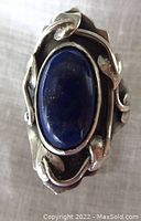 Front view of vintage sterling silver ring showing oval lapis lazuli stone and floral silver design.