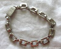 Photo of entire bracelet laid flat showing 10 rectangular links and push-in clasp marked 925